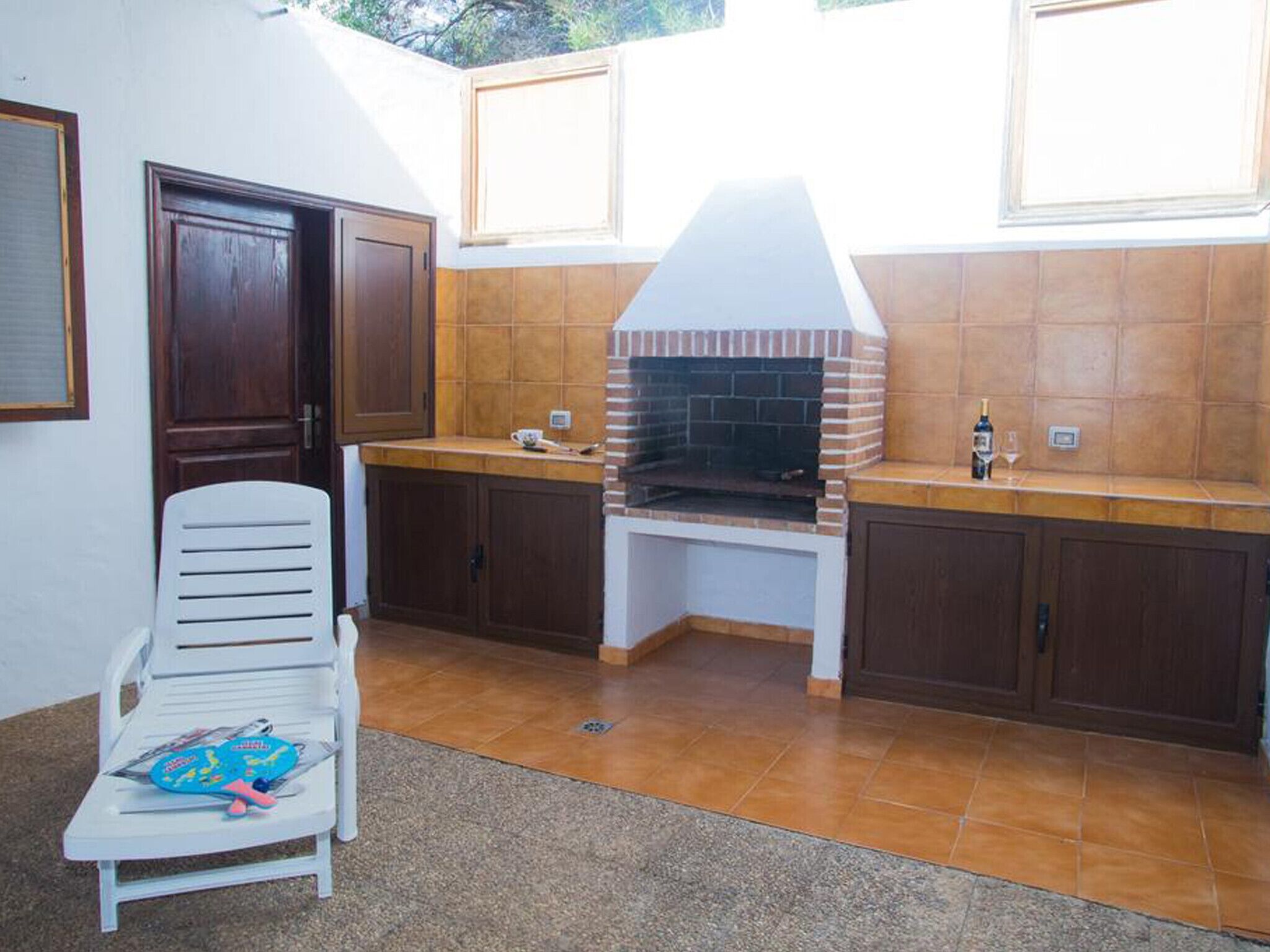 A kitchen with a brick oven, wooden cabinets, and a white chair.