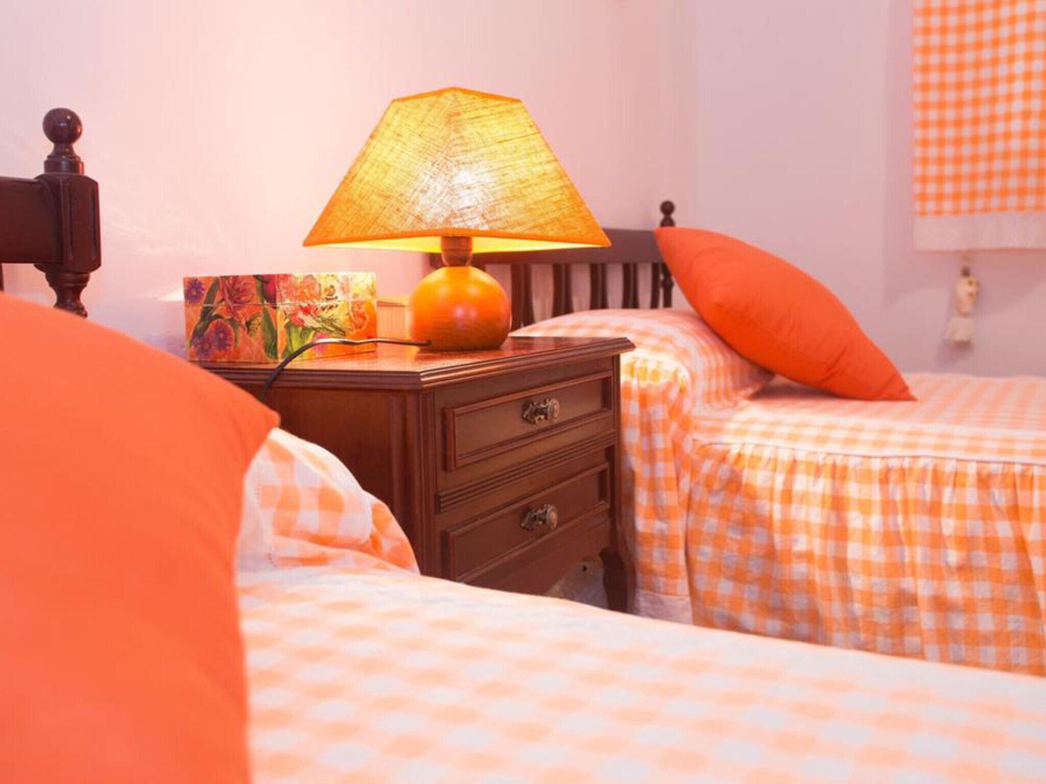 Een slaapkamer met twee bedden, een nachtkastje, een lamp en een schilderij.