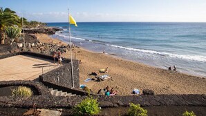 Une plage avec un drapeau, des gens et un ciel dégagé.