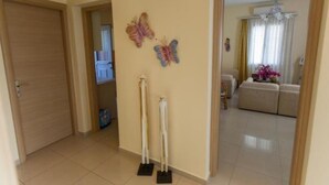 Un couloir avec une porte fermée, un balai et une serpillière appuyés contre le mur.