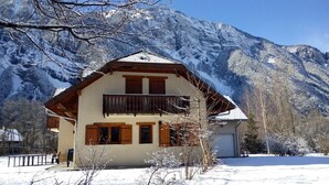 A two-story chalet with a balcony, set against a snowy mountain backdrop. - IMPRESSIVE HOUSE IN BOURG D’OISANS - SLEEPS 14 (Bourg d'Oisans)
