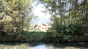 A house surrounded by dense greenery and a calm river. - IMPRESSIVE HOUSE IN BOURG D’OISANS - SLEEPS 14 (Bourg d'Oisans)
