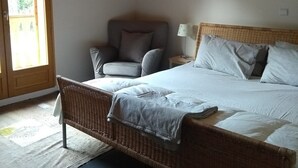 A bedroom with a large bed, a chair, a lamp, and a window. - IMPRESSIVE HOUSE IN BOURG D’OISANS - SLEEPS 14 (Bourg d'Oisans)