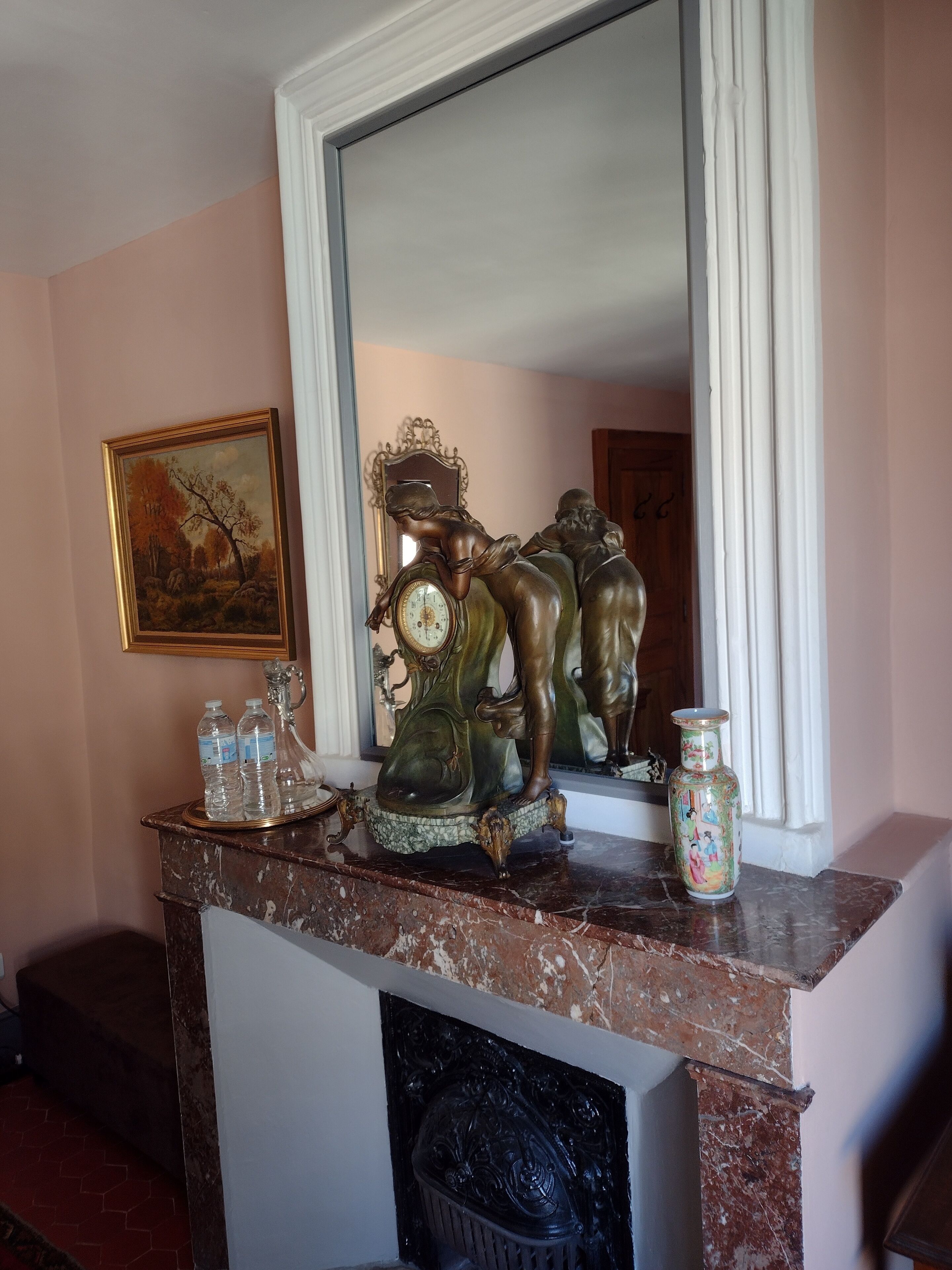 A marble fireplace with a decorative clock and a vase.