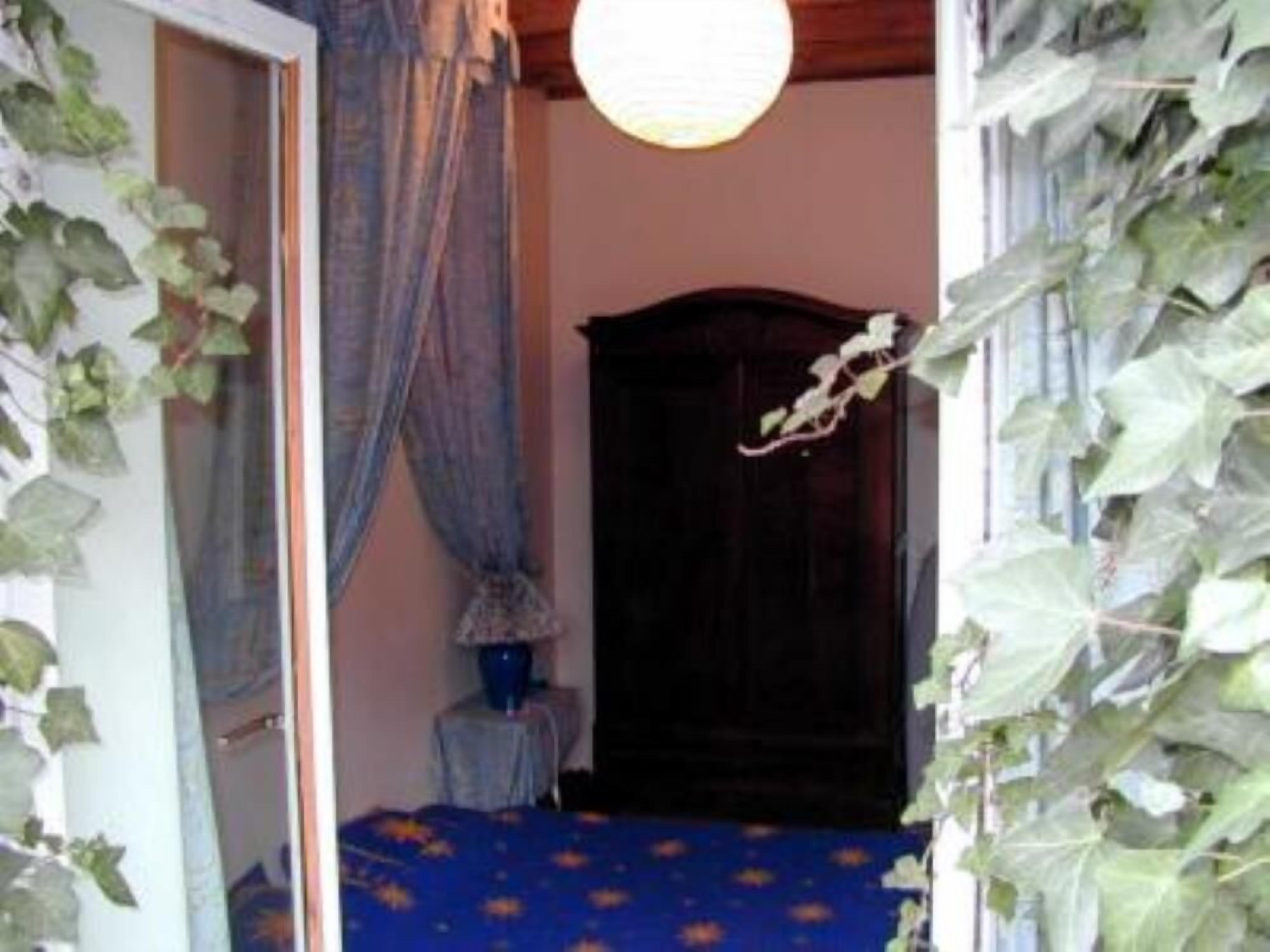 Une pièce comprenant un lit, une armoire en bois sombre, une petite table avec une lampe et une fenêtre avec des rideaux.