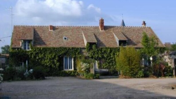 A two-story house with a sloped roof, ivy-covered walls, and a driveway leading to the entrance. - Chevannes: House with character (Chevannes)