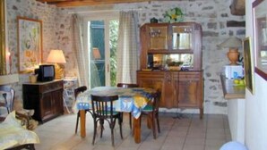 A rustic dining area with a stone wall, wooden ceiling, and a table set for two. - Chevannes: House with character (Chevannes)