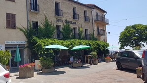 A building with a stone facade, a sign for 'Hotel Jeuse Jour', and outdoor seating with umbrellas. - A 2 bedrooom 2 bath home home with stunning, elevated views, 24km from the sea. (Berre-Les-Alpes)