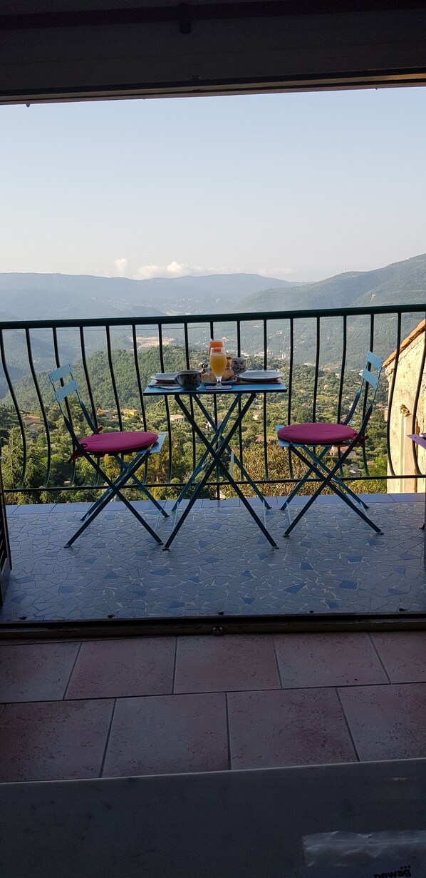 Un balcone con tavolo e sedie, affacciato su un paesaggio montuoso.