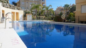 Una piscina con agua cristalina azul, rodeada de edificios y palmeras.