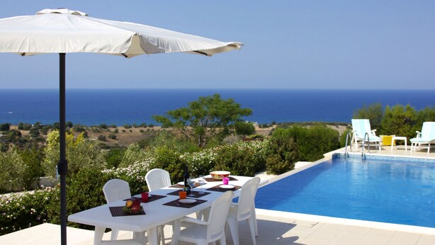 A poolside dining area with a table set for two, a white umbrella, and a view of the sea. - Indulge Yourselves! Perfect Location ~ Private Pool ~ Spectacular Panorama (Neo Chorio)