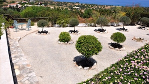 A landscaped garden with neatly arranged shrubs and a seating area with chairs. - Indulge Yourselves! Perfect Location ~ Private Pool ~ Spectacular Panorama (Neo Chorio)