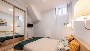 Une chambre à coucher avec un lit, un miroir, une fenêtre et une lampe fixée au mur.