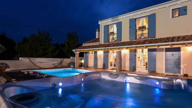 Ein Poolbereich mit Whirlpool und einem Haus im Hintergrund.