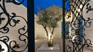 Ein Innenhof mit Baum, einem Metallgitter und einem Gebäude mit blauen Türen.