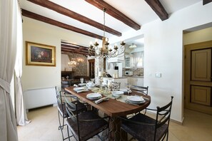 A dining area with a wooden table set for six, surrounded by upholstered chairs. A chandelier hangs from the ceiling, and a painting is visible on the wall. - Villa Mek ZadarVillas (Pridraga)