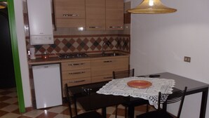 Una cocina compacta con una mesa, sillas y un refrigerador pequeño.