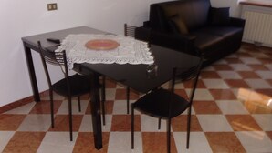 Un comedor con mesa y sillas, un sofá negro y un suelo a cuadros.