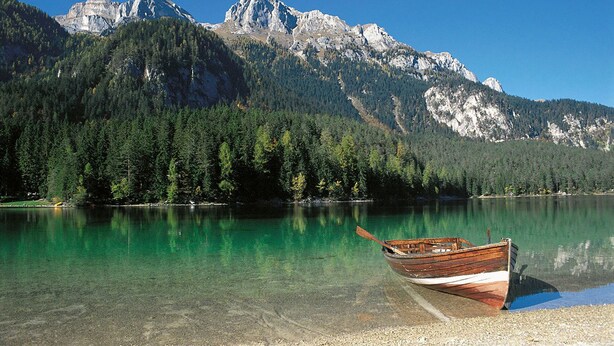 Un barco en un lago despejado con montañas al fondo.