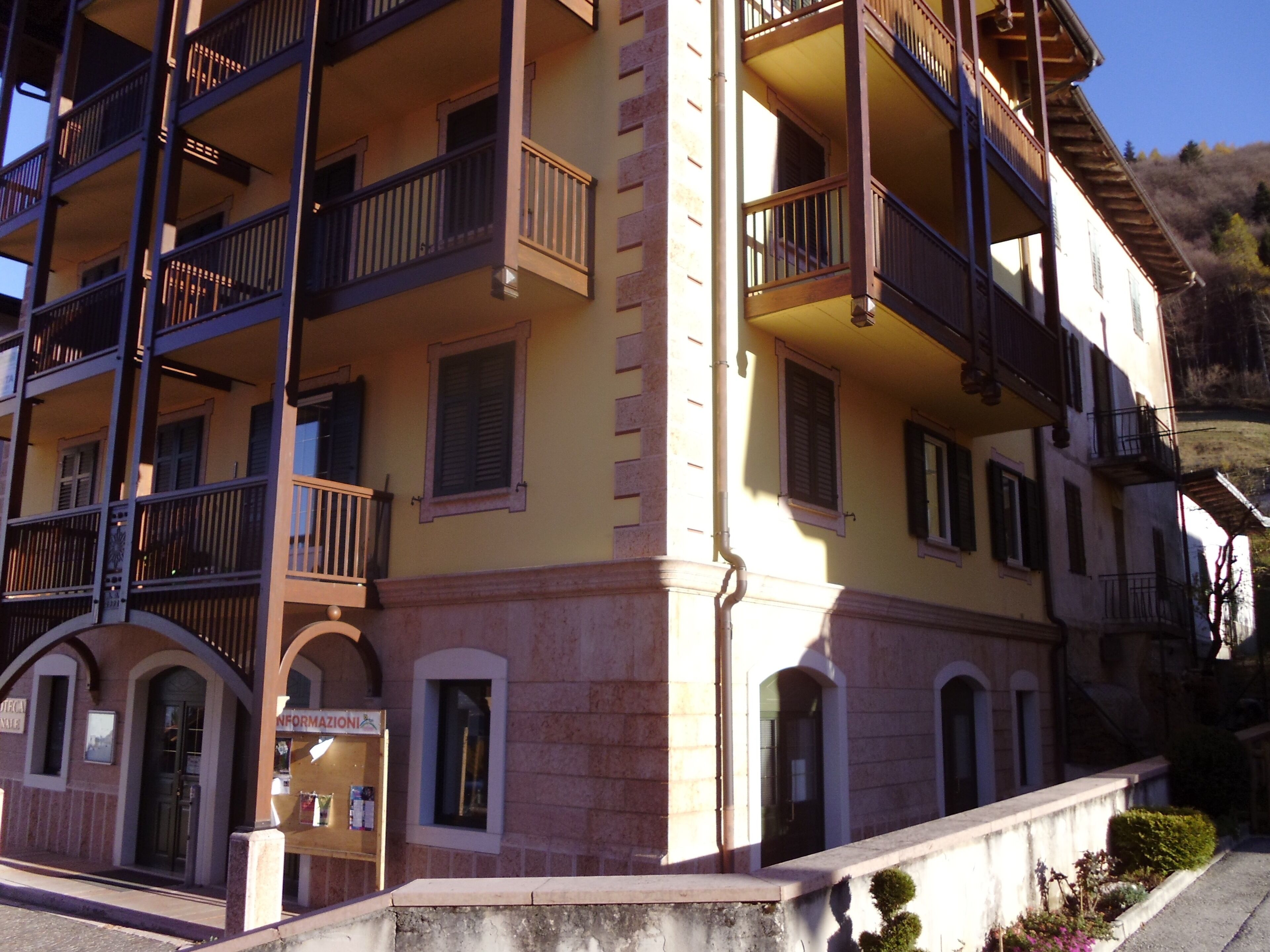 A multi-story building with balconies, a ground-level entrance, and a sign indicating a business on the ground floor.
