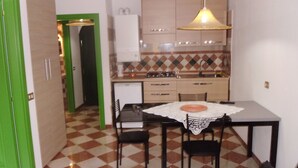 Una cocina compacta con mesa, sillas y un refrigerador pequeño.