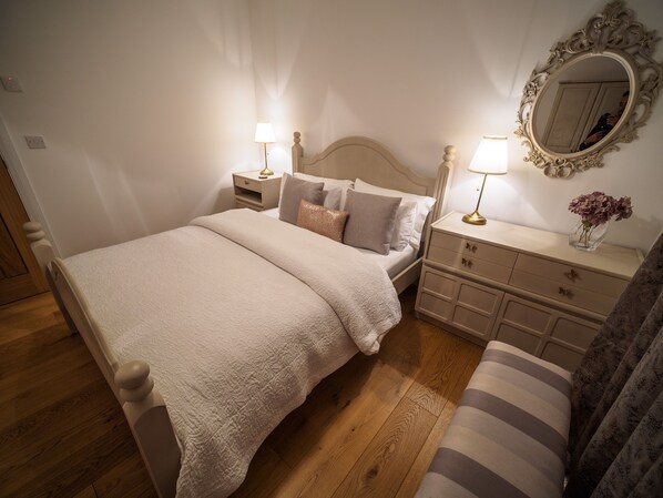 A neatly arranged bedroom with a bed, bedside tables, a dresser, and a mirror.