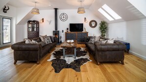 A loft-style living room with a fireplace, two sofas, a coffee table, and a TV. - Taymore Lodge, your home away from home... (Kenmore)
