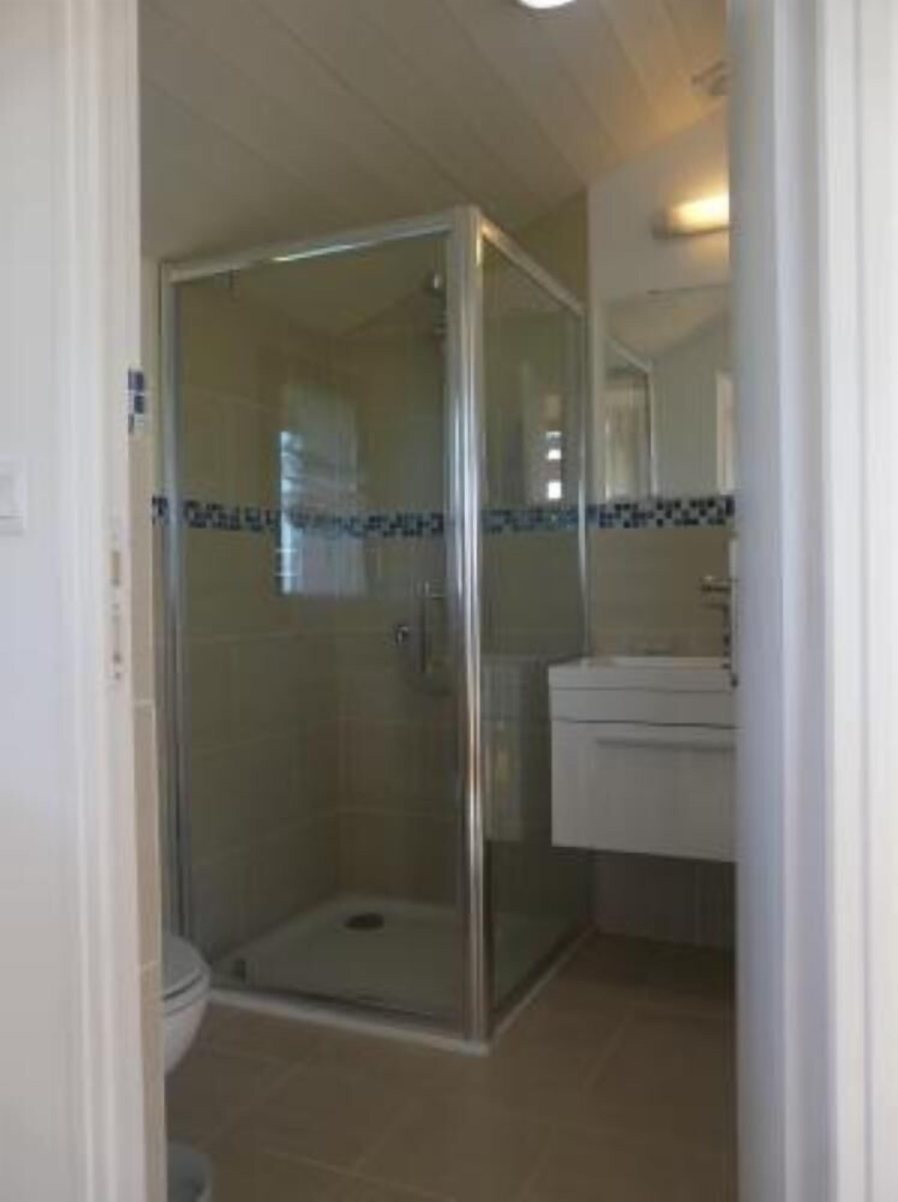 A bathroom with a glass-enclosed shower, a toilet, and a sink with a mirror above it.