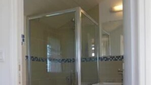 A bathroom with a glass-enclosed shower, a toilet, and a sink with a mirror above it. - House / Villa - Talais (Talais)