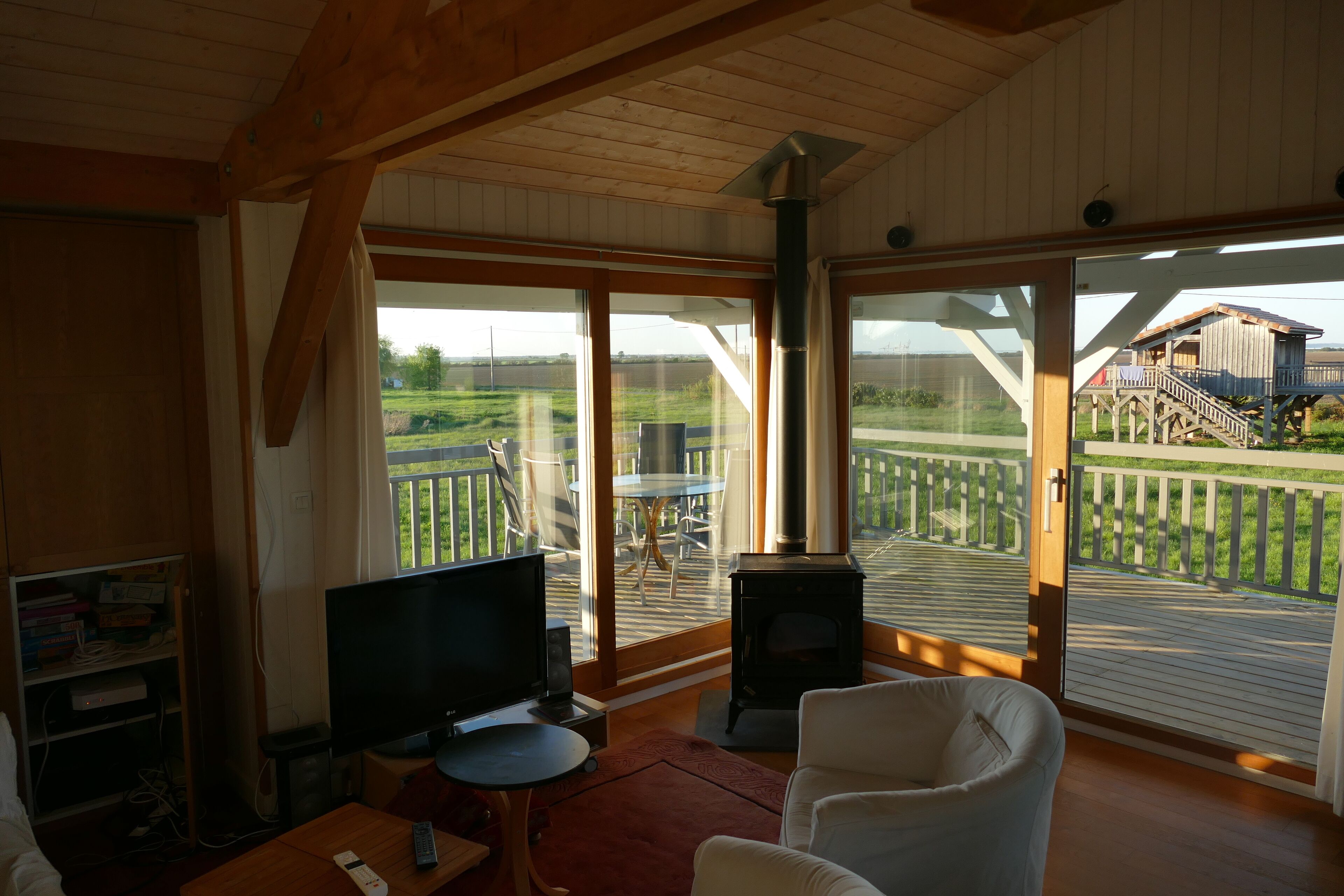 A cozy living room with a TV, a fireplace, and large sliding glass doors leading to an outdoor deck.