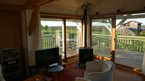 A cozy living room with a TV, a fireplace, and large sliding glass doors leading to an outdoor deck. - House / Villa - Talais (Talais)