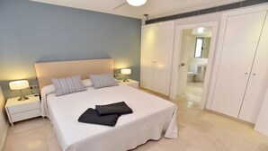 Quarto com uma cama grande, duas mesas de cabeceira com abajures, um guarda-roupa e um banheiro visível através de uma porta aberta.