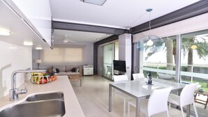 Cozinha moderna com área de jantar, janelas amplas e vista para palmeiras.
