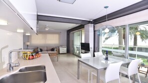A modern kitchen with a dining area, large windows, and a view of palm trees.