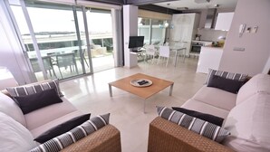 Uma sala de estar moderna com um conjunto de sofás, uma mesa de centro e uma televisão.