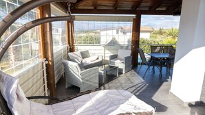 Un patio ensoleillé, doté de meubles en osier et offrant une vue sur le paysage environnant.