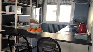 Una cucina compatta con isola centrale, una finestra con tende e un termosifone.
