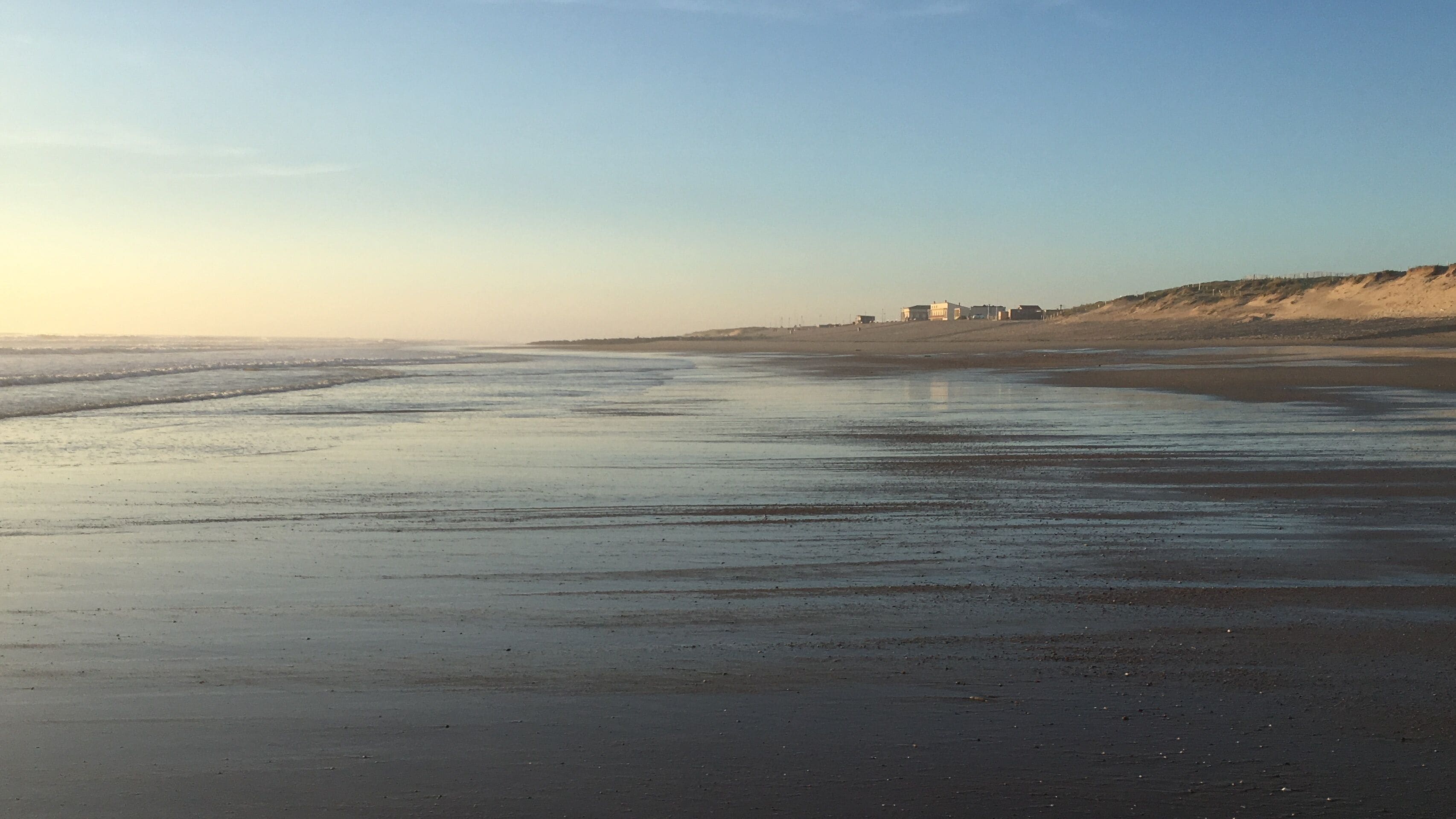Une plage avec une vaste étendue de sable et des vagues douces.