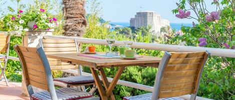 Ein Holztisch mit zwei Stühlen, Blick auf das Meer und eine Palme.