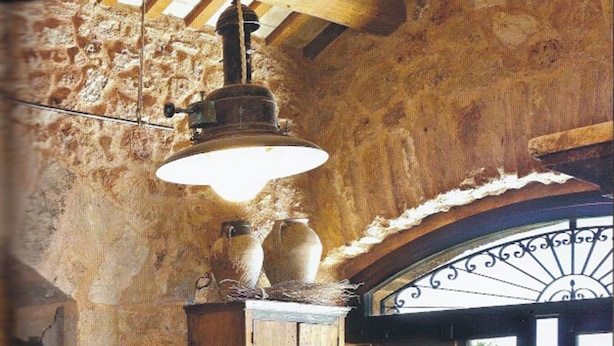 A rustic dining area with a wooden table, chairs, and a hanging light fixture.