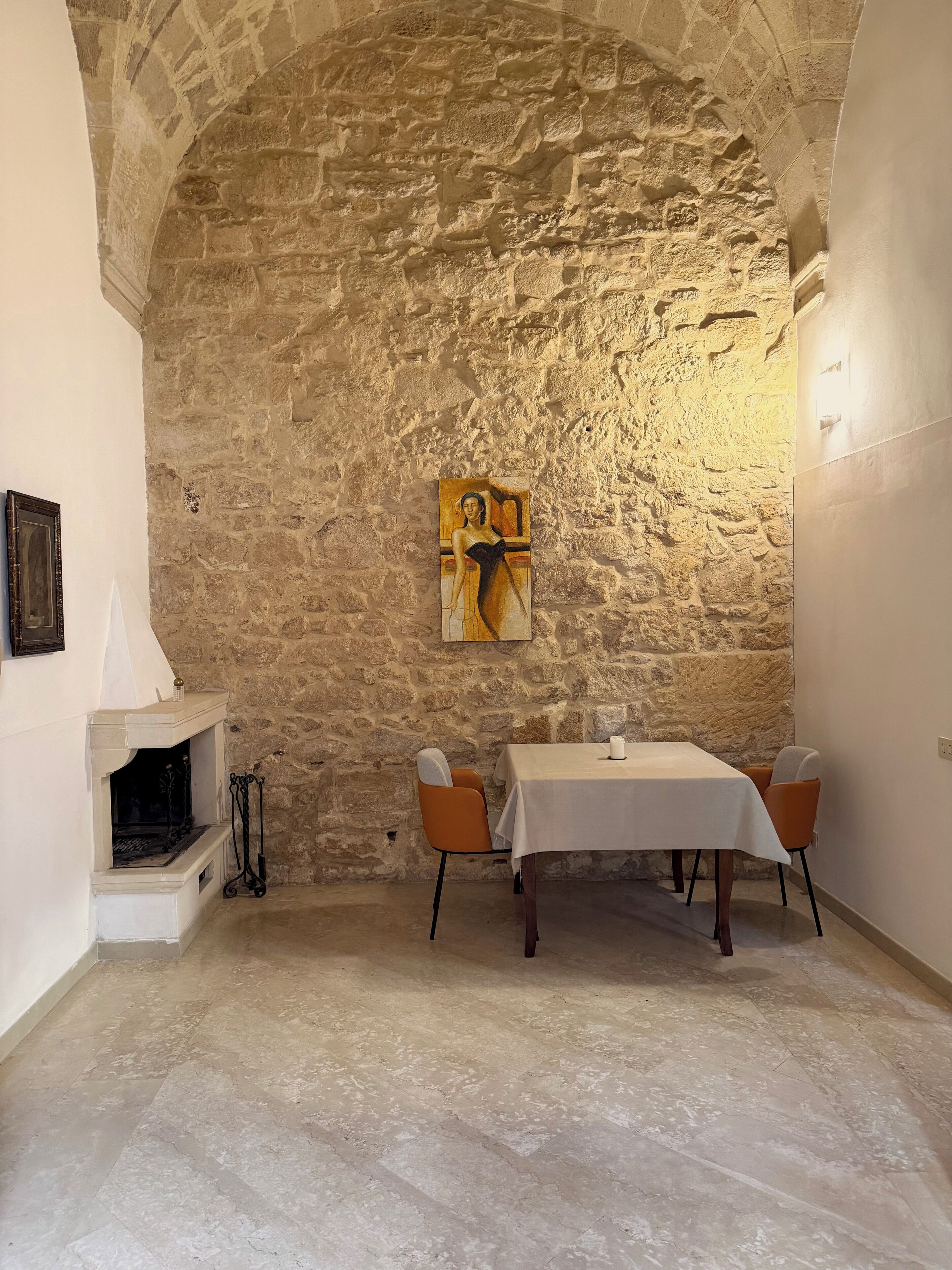 A dining area with a stone wall, a fireplace, and a table with chairs.