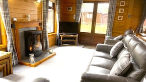 Una sala de estar acogedora con chimenea, sofá de cuero y televisor.