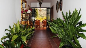 A hallway with a tiled floor, potted plants, a mirror, and a door leading to an outdoor area. - Parador del Silo (Alhambra, beach, snow and Alpujarra) Air Conditioning and Wifi (Cónchar)