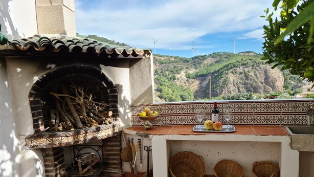 A patio with a brick oven, a tiled backsplash, and a view of wind turbines in the distance. - Parador del Silo (Alhambra, beach, snow and Alpujarra) Air Conditioning and Wifi (Cónchar)