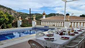 A dining area with a pool view, white chairs, and a table set for a meal. - Parador del Silo (Alhambra, beach, snow and Alpujarra) Air Conditioning and Wifi (Cónchar)
