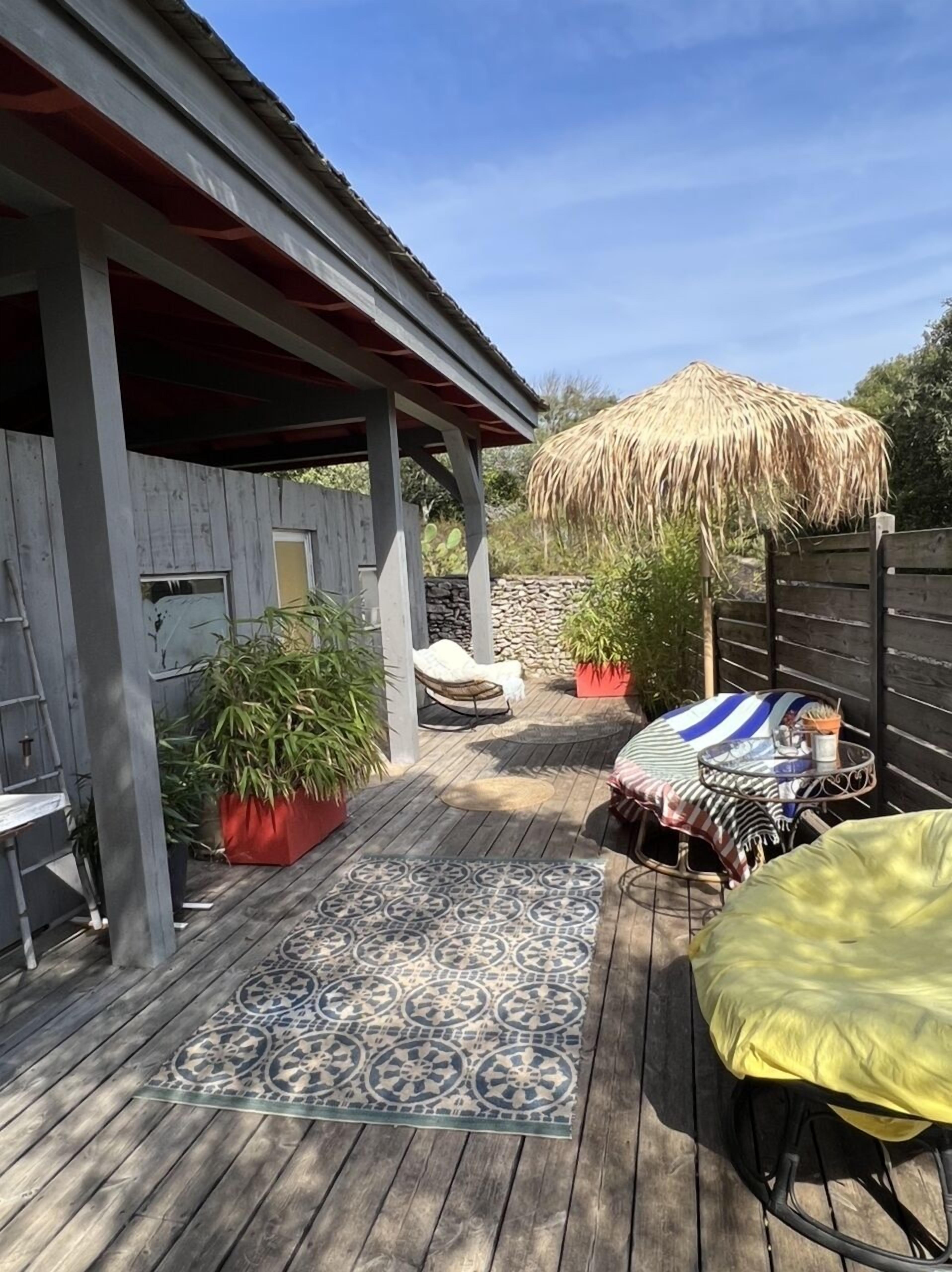 En træterrasse med måtte, bindingsværk og plantekasser.