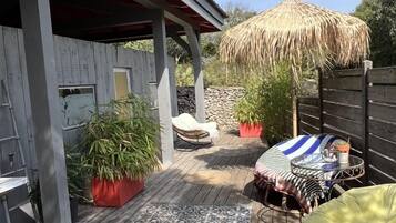 En træterrasse med måtte, bindingsværk og plantekasser.