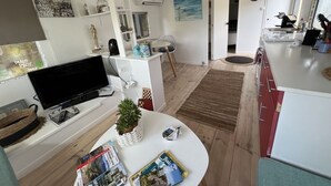 A compact living space with a TV, a small dining area, and a kitchen. - Zen cabin in the bush (Bonifacio)