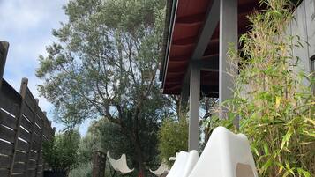 Un espacio al aire libre cubierto con una silla lounge blanca sobre un tapete de diseño azul, una terraza de madera y una cerca de madera.