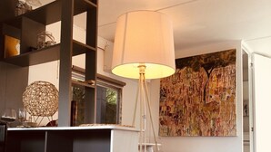 A living room with a round table, books, a lamp, and a wall with a colorful abstract painting. - Zen cabin in the bush (Bonifacio)